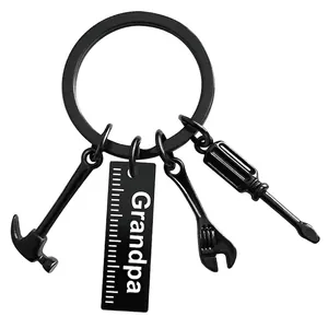 Macro detail of black matte keychain with grandpa tag, hammer, wrench, and screwdriver