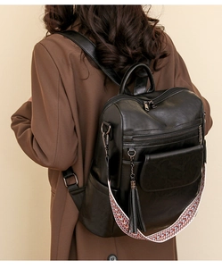 Detail of black PU leather backpack featuring colorful woven straps and fringe tassel charm