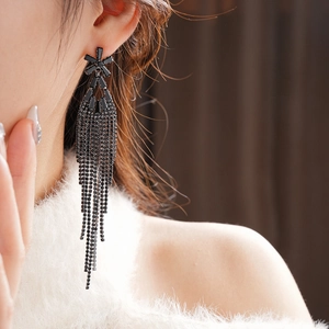 Gros plan sur d'élégantes boucles d'oreilles à pompons noirs avec fleurs en strass