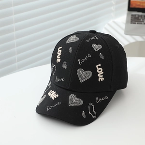 Détail des broderies de cœurs beiges et du texte LOVE sur la casquette en coton noir