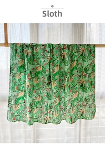 Detail of bamboo cotton muslin baby blanket with jungle sloth and tropical leaf patterns
