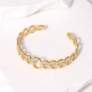 Detailed close-up of golden stainless steel open bracelet with interlocking circular links