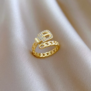 Detail of gold belt buckle ring with sparkling zircons on elegant champagne silk fabric