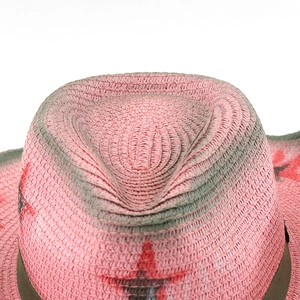 Detail of pink Y2K straw cowboy hat with distressed texture and red star emblem