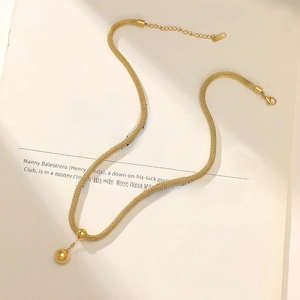 Minimalist stainless steel 14K gold plated ball pendant necklace on a book background