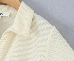 Detailansicht der cremeweißen Waffelstrick-Struktur auf einem Polokleid für Damen