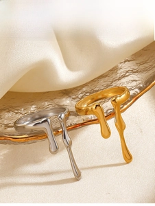 Macro detail of irregular lava style open rings in gold and silver on textured glass