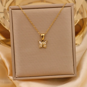 Close-up of golden butterfly pendant with clear zircons in a beige jewelry box with silk