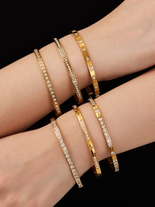 Dettaglio di bracciali in acciaio placcati oro 18k con zirconi incastonati su una modella