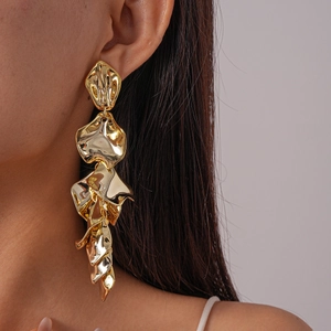Detail of layered gold petal earrings featuring organic textures on a female model