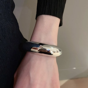 Close-up of a chunky irregular silver cuff bracelet with a polished mirror finish on a wrist