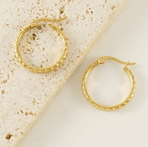 Close-up of golden 18K titanium steel hoop earrings with woven rope texture on stone base