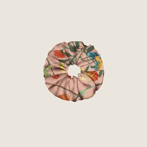 Detailed close-up of pink silk hair scrunchie with retro floral and bird jungle patterns