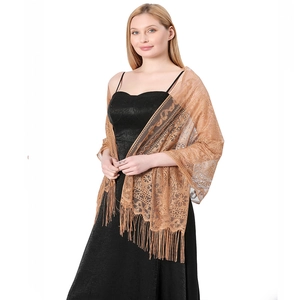 Close-up of golden brown lace shawl with hollow floral patterns and long fringe tassels