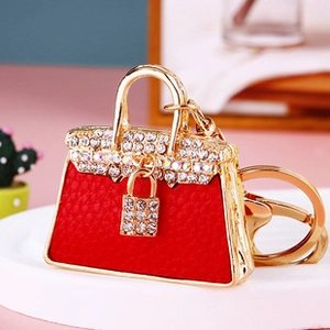 Detail of red leather mini bag keychain with gold metal hardware and crystal accents