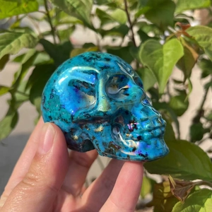 Macro view of a 7cm aura crystal skull featuring iridescent blue metallic finish