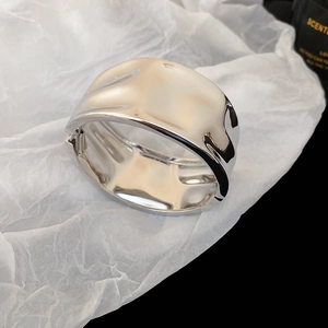 Detailed macro view of wide irregular hammered silver metal bangle with hinge closure