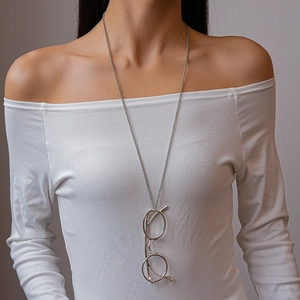 Close-up of a long silver bead chain necklace with a unique round glasses pendant