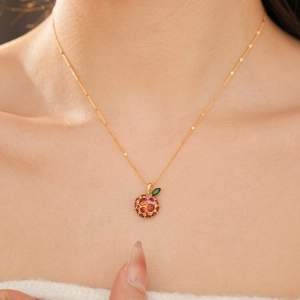 Close-up of 14k gold plated apple pendant with vibrant red and purple zircon stones