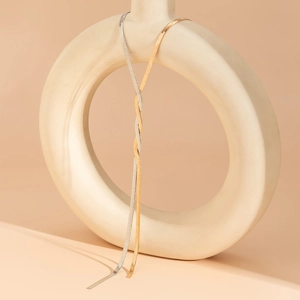 Nahaufnahme minimalistischer flacher Schlangenketten in Gold und Silber auf Keramikring