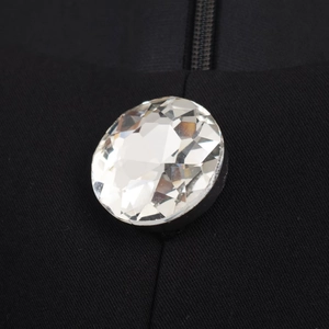 Close-up of sparkling crystal rhinestone button on black fabric with zipper detail