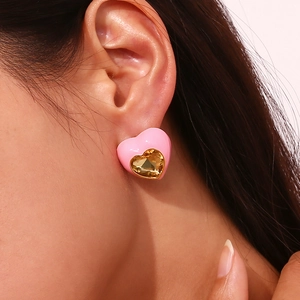 Détail de la boucle d'oreille cœur rose avec zircone dorée portée sur l'oreille