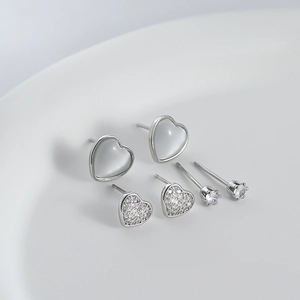 Detailed view of silver heart earrings set featuring cat-eye stones and cubic zirconia