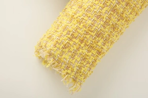 Macro texture of yellow and white tweed fabric with fringe details for jacket