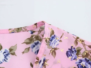 Dettaglio dello scollo di camicetta boho rosa con stampe floreali blu e oro
