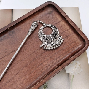 Detail of vintage silver hair stick with floral tassel charms on wooden tray