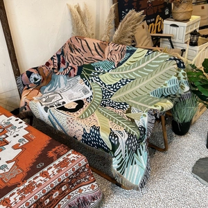 Detailed view of bohemian woven blanket featuring pink tiger and tropical leaf patterns
