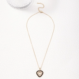 Golden heart pendant necklace with deep red zircon stones on white textured surface