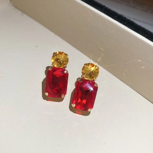 Detail of square red and round yellow crystal studs with gold-plated claw settings