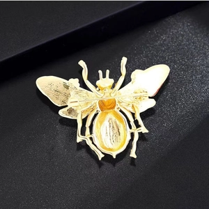Vintage golden bee brooch with detailed metallic texture shown on a dark background