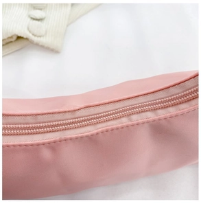 Close-up of the smooth zipper closure on a light pink nylon crossbody crescent bag