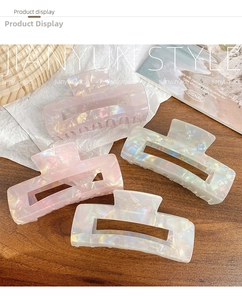 Close-up of iridescent hair claws with pearlescent finish on wooden display surface