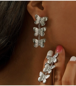 Détail de boucles d'oreilles papillon en argent avec texture métal brossé sur un modèle