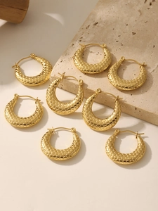 Macro detail of gold U-shaped earrings featuring intricate honeycomb textured patterns