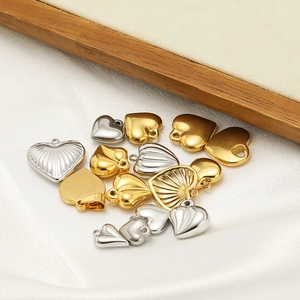 Mix of 18K gold plated and silver stainless steel heart pendants on white silk background