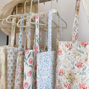 Gros plan de sacs fourre-tout en coton aux imprimés floraux suspendus sur un cintre