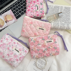 Detailed view of four pink floral and rabbit quilted cotton cosmetic pouches with zippers