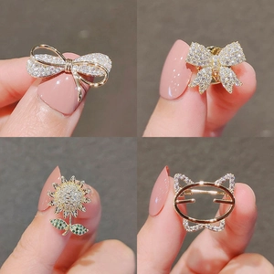 Macro detail of four mini zircon crystal brooches held by fingers on dark background