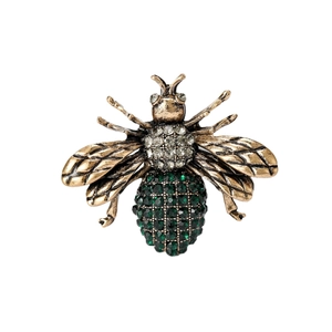 Vintage gold bee brooch with emerald green and white rhinestones on a white background