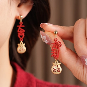 Detailed macro view of vintage red enamel lucky bag earrings with gold tassels