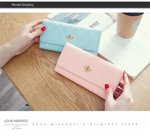 Close-up of long trifold wallets in blue and pink featuring crown metal decor and quilted texture