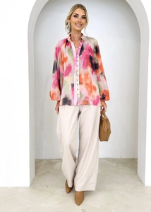 Modèle portant une chemise à imprimé aquarelle coloré avec un pantalon beige taille haute