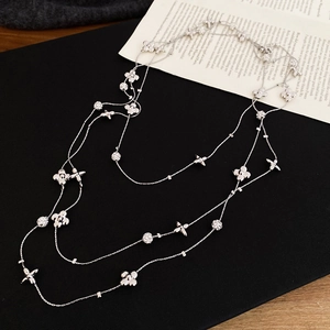 Macro detail of silver layered necklace featuring clover and star pendants with pavé diamonds