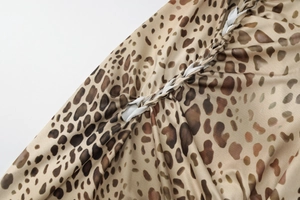Detailed macro view of leopard print chiffon fabric featuring a white braided strap detail