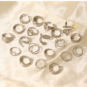 Flat lay of multiple silver vintage stainless steel rings on a champagne satin background