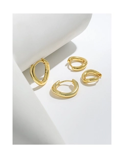 Detailed view of four minimalist irregular gold hoop earrings on a white background